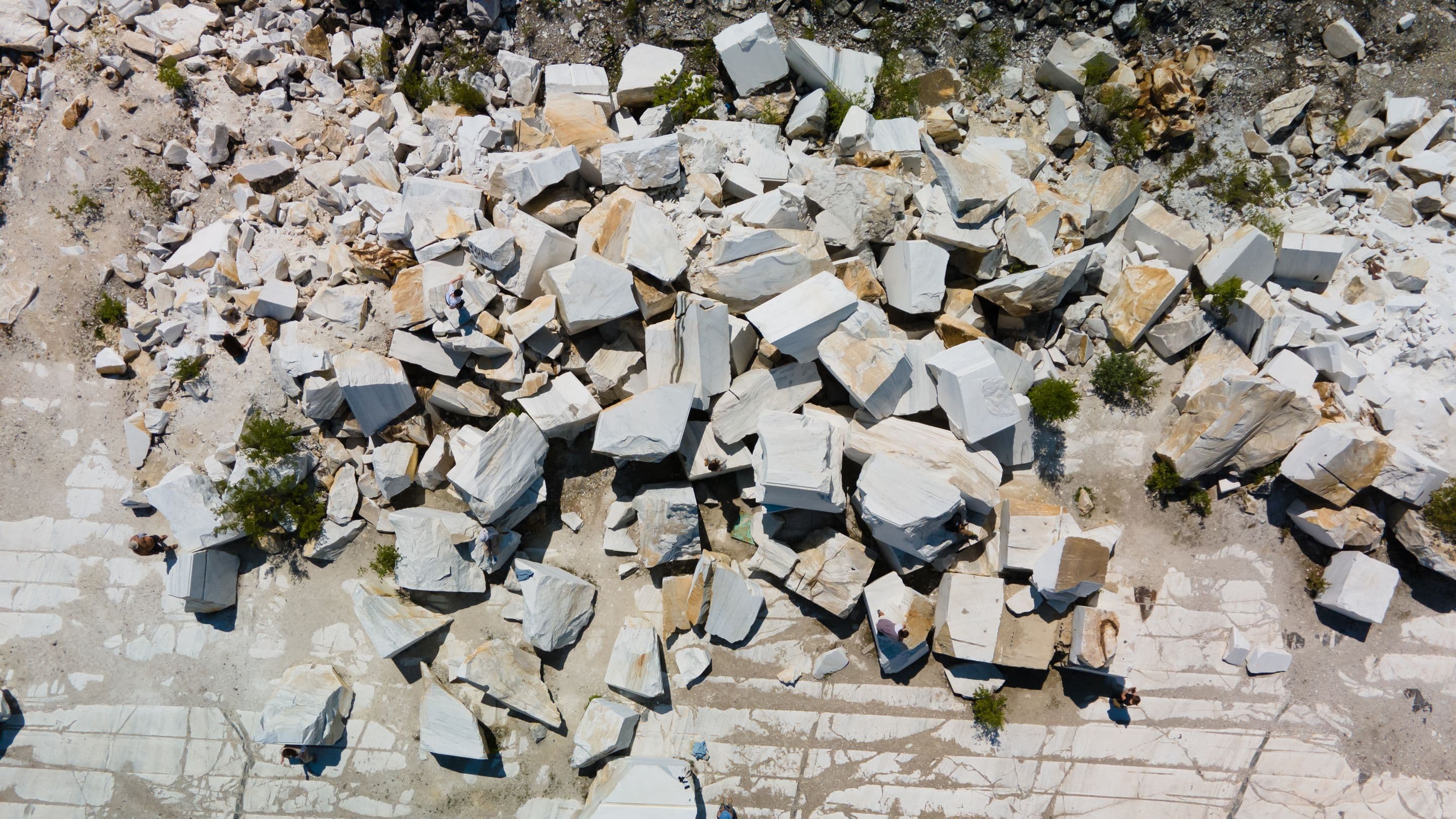 Aerial view of large marble blocks spread across a sunlit quarry floor
