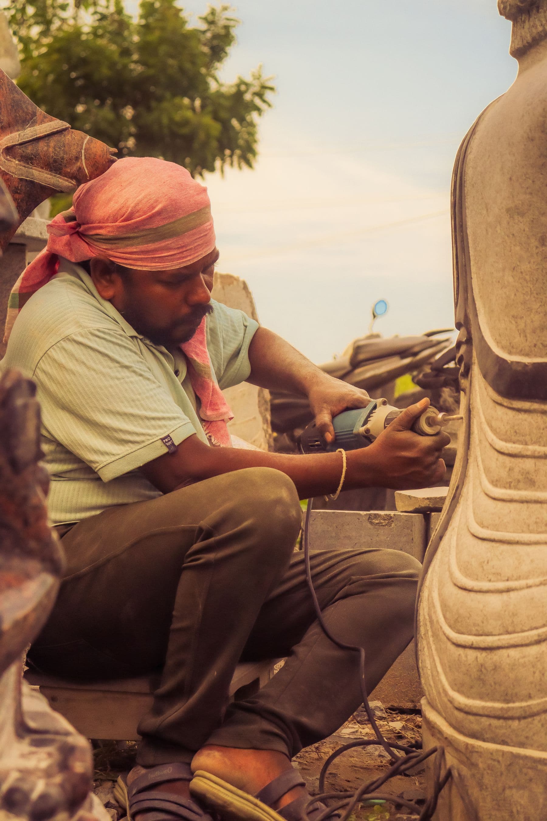 A stonemason absorbed in finishing a carved stone piece at golden hour
